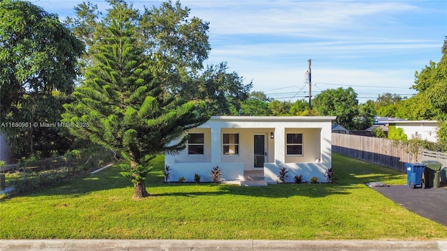 view of front facade with stucco siding, a front lawn, and fence