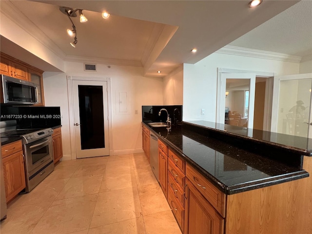 kitchen featuring kitchen peninsula, dark stone counters, sink, crown molding, and stainless steel appliances