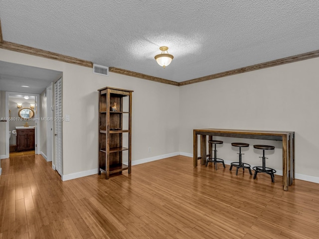 interior space featuring a textured ceiling, crown molding, and light hardwood / wood-style flooring