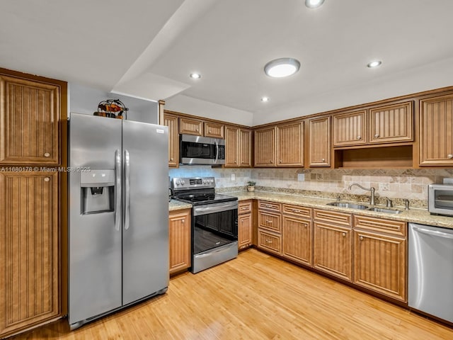 kitchen featuring light hardwood / wood-style floors, decorative backsplash, sink, appliances with stainless steel finishes, and light stone counters