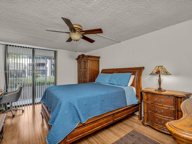 bedroom with ceiling fan, access to exterior, a textured ceiling, and light hardwood / wood-style flooring