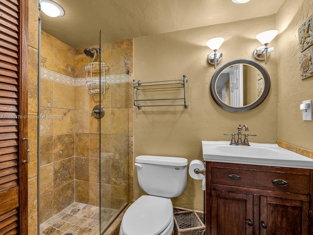 bathroom with toilet, tiled shower, and vanity