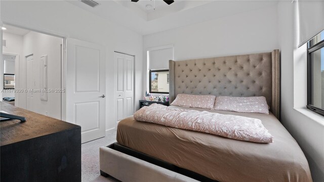 bedroom featuring ceiling fan, multiple windows, and light colored carpet