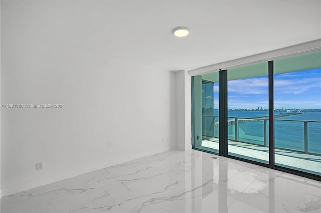 unfurnished room with a water view, a wall of windows, and a wealth of natural light