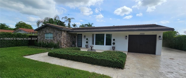 ranch-style home featuring a front lawn and a garage