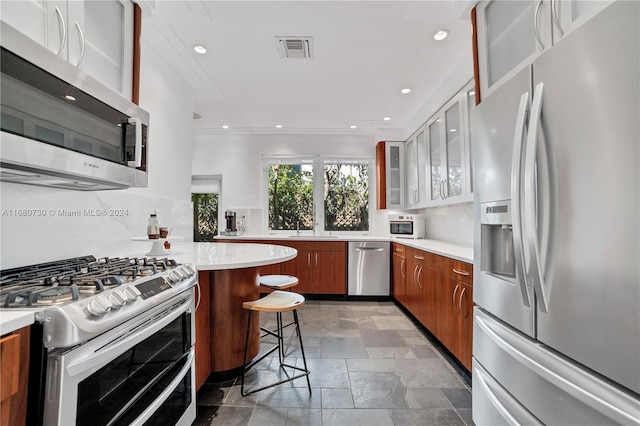 kitchen featuring decorative backsplash, appliances with stainless steel finishes, a kitchen breakfast bar, white cabinetry, and sink