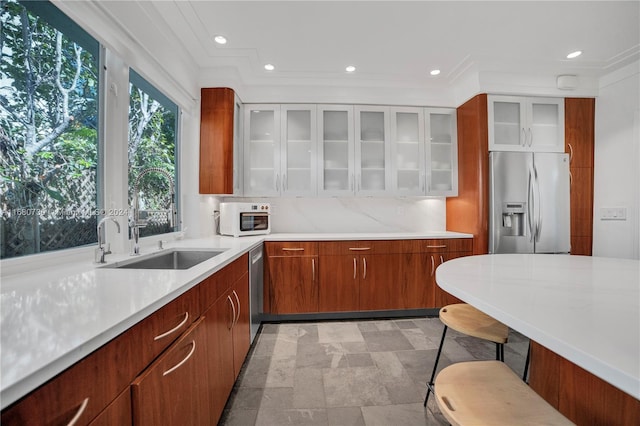 kitchen featuring decorative backsplash, a breakfast bar, ornamental molding, sink, and stainless steel appliances