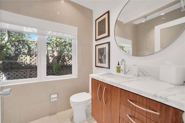 bathroom featuring toilet, vanity, tile walls, and tile patterned flooring