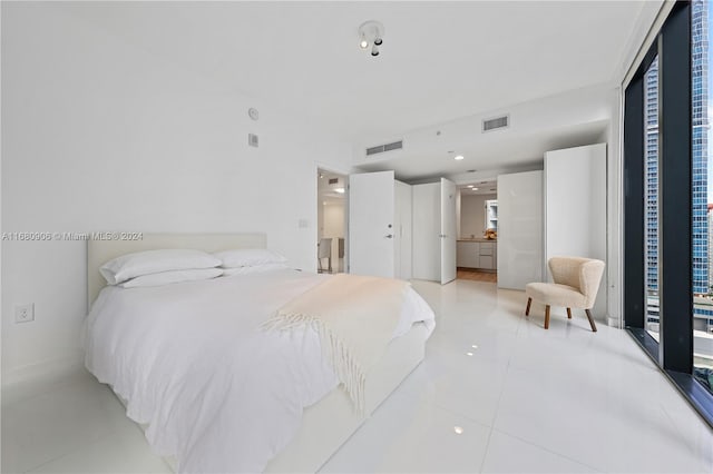 bedroom featuring ensuite bath, light tile patterned flooring, and access to exterior