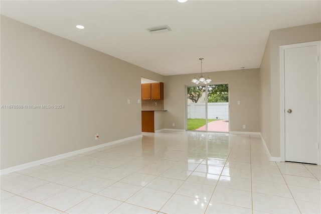 empty room featuring light tile patterned floors and an inviting chandelier