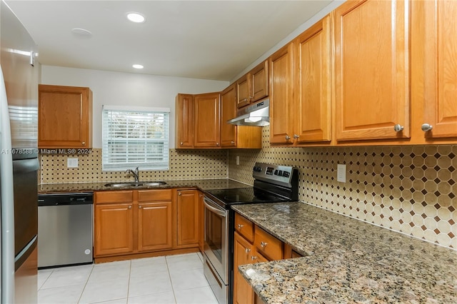 kitchen featuring decorative backsplash, light tile patterned floors, dark stone counters, sink, and stainless steel appliances