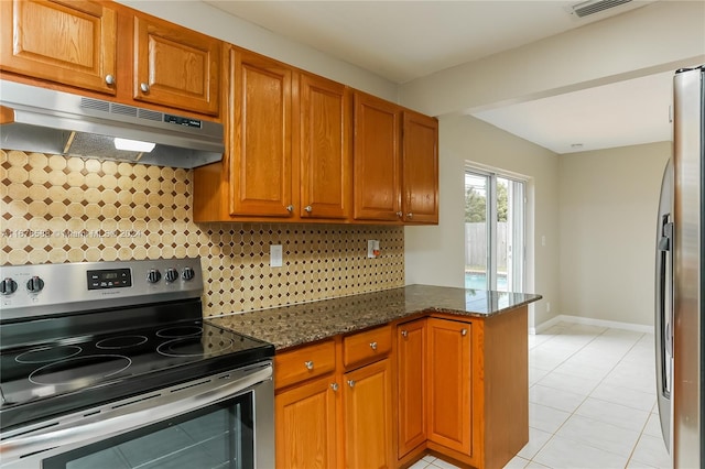 kitchen with kitchen peninsula, dark stone countertops, light tile patterned floors, appliances with stainless steel finishes, and tasteful backsplash