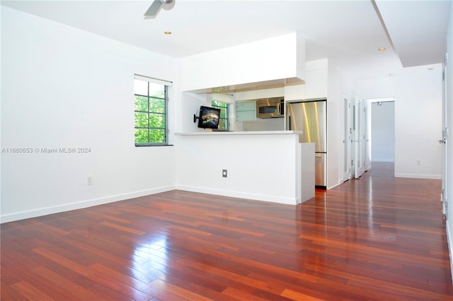 unfurnished living room featuring dark wood-type flooring and ceiling fan