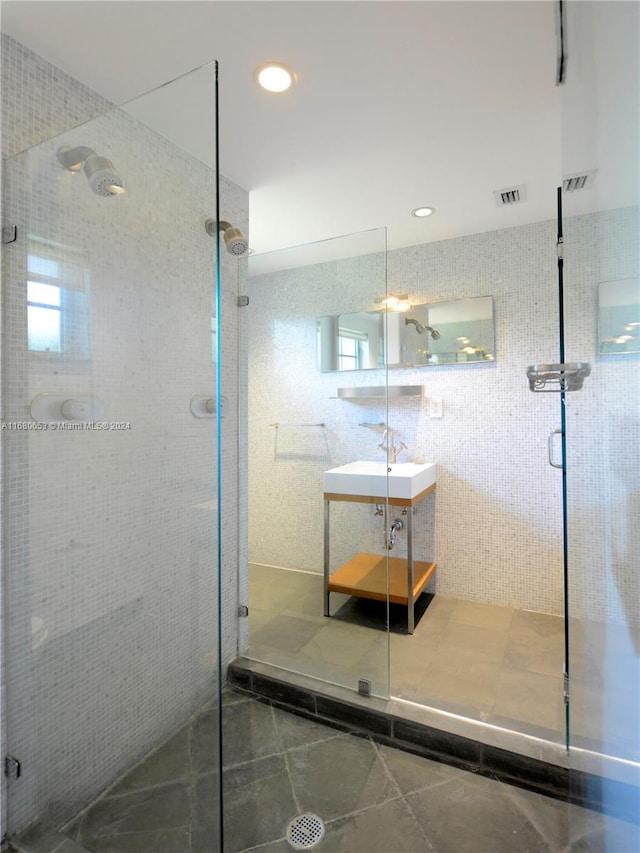 bathroom with vanity, tile walls, a shower with shower door, and tile patterned flooring