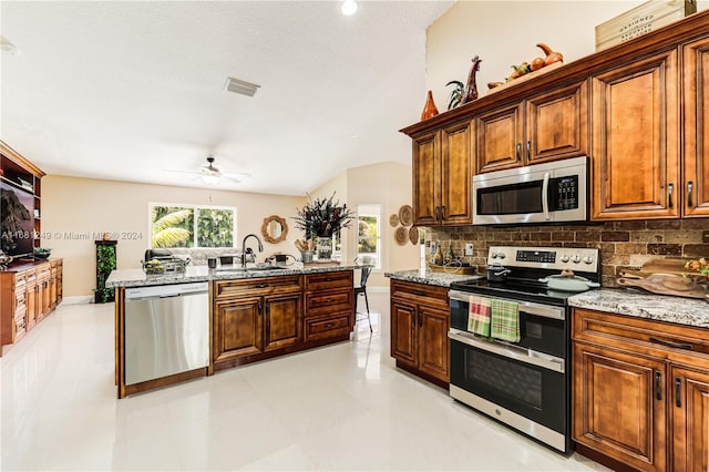 kitchen featuring light stone countertops, appliances with stainless steel finishes, sink, and ceiling fan