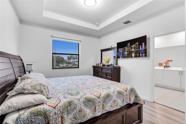 bedroom featuring a tray ceiling and light wood-type flooring