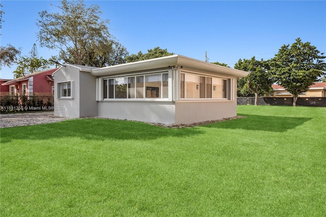 view of home's exterior with a sunroom and a lawn