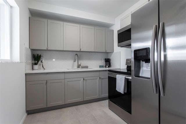 kitchen with appliances with stainless steel finishes, decorative backsplash, sink, and gray cabinetry