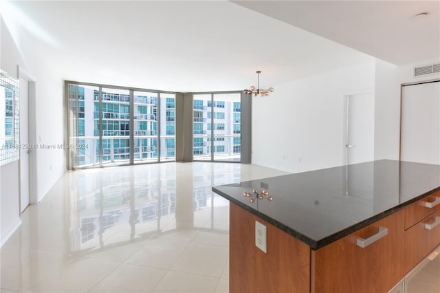 kitchen featuring a chandelier, a large island, light tile patterned flooring, pendant lighting, and a wall of windows