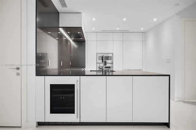 kitchen featuring white cabinets, tasteful backsplash, beverage cooler, stovetop, and stainless steel oven