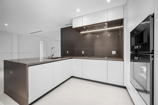 kitchen with white cabinets, tasteful backsplash, sink, and cooktop