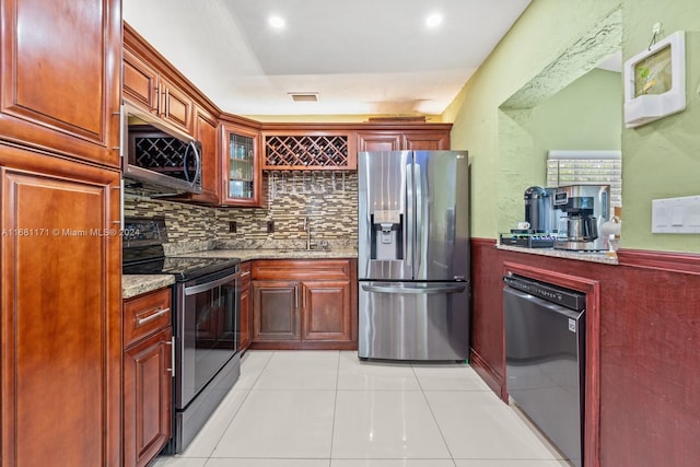 kitchen featuring stainless steel appliances, backsplash, sink, light stone countertops, and light tile patterned floors