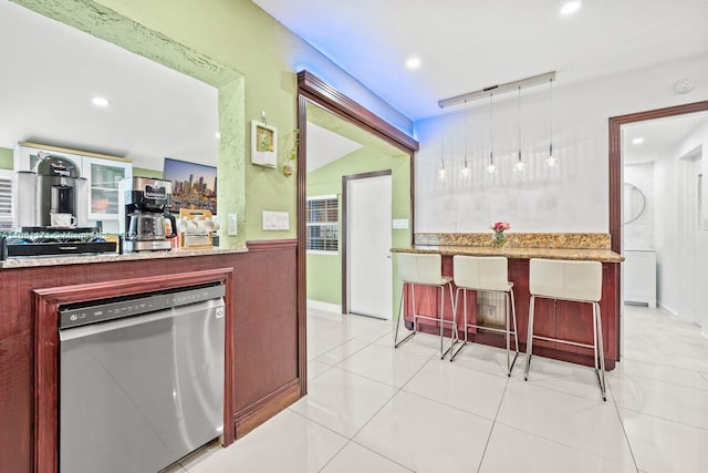 kitchen featuring dishwasher, a kitchen bar, kitchen peninsula, pendant lighting, and light tile patterned floors