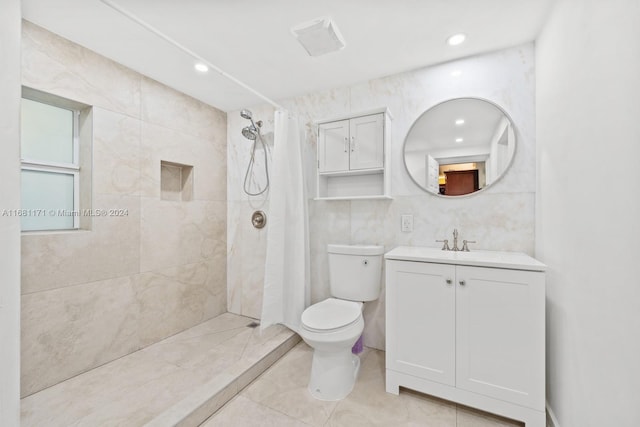 bathroom featuring tile patterned floors, toilet, vanity, tile walls, and walk in shower