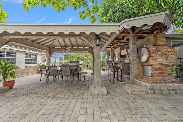 view of patio featuring an outdoor fireplace, a gazebo, and exterior bar