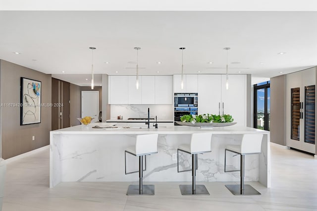 kitchen with a spacious island, double oven, white cabinets, and hanging light fixtures