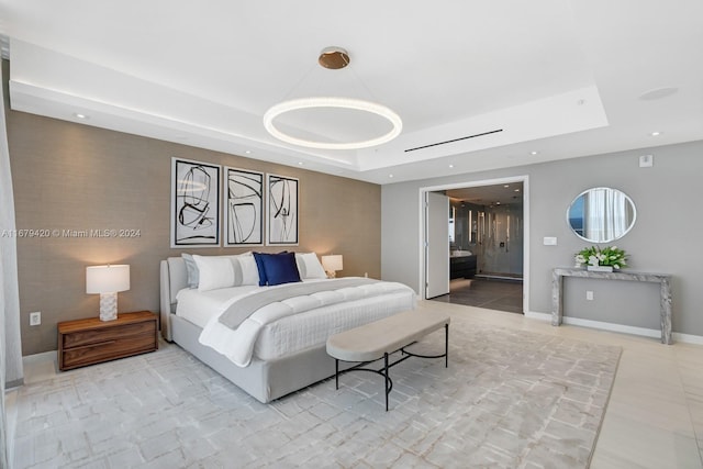 bedroom with ensuite bathroom and a tray ceiling