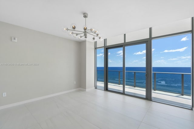 spare room with a chandelier, a water view, and expansive windows