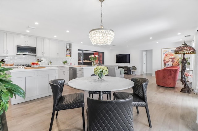 dining room with a notable chandelier and light wood-type flooring