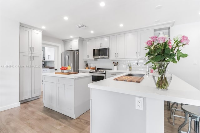 kitchen featuring a center island, white cabinets, sink, appliances with stainless steel finishes, and light hardwood / wood-style floors