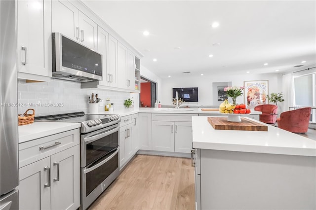 kitchen featuring backsplash, kitchen peninsula, white cabinets, and stainless steel appliances