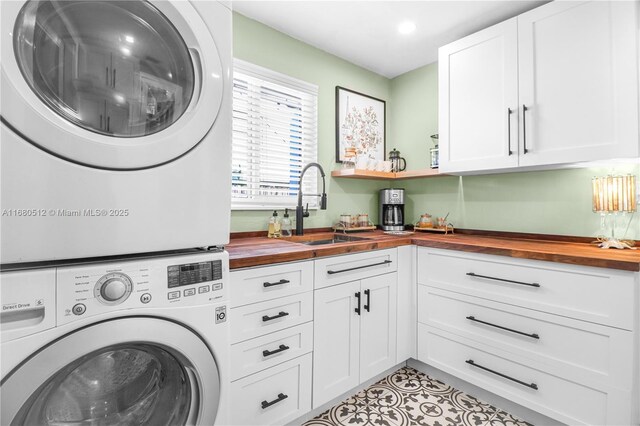 laundry room featuring light tile patterned flooring, stacked washer and dryer, and sink