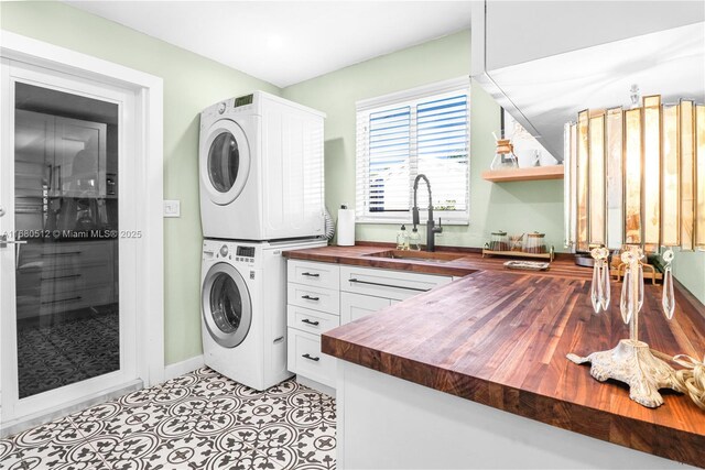 washroom with cabinets, sink, light tile patterned floors, and stacked washer / dryer