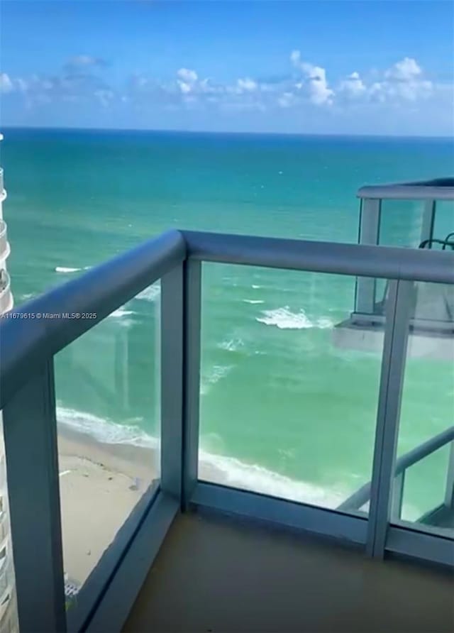 balcony featuring a water view and a beach view