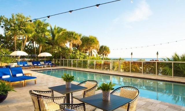 view of pool featuring a water view and a patio area