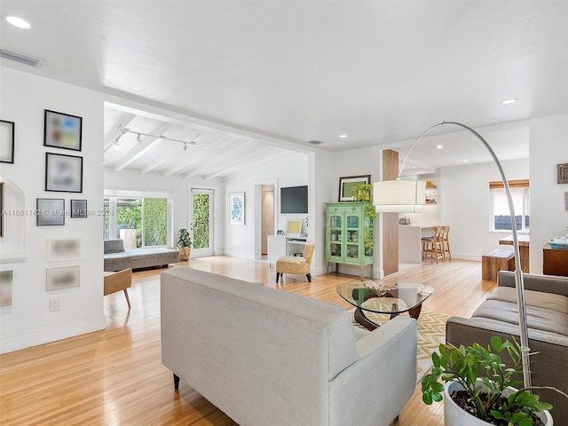 living room with light wood-type flooring and vaulted ceiling with beams