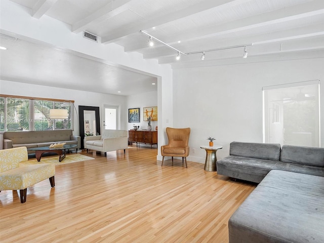 living room featuring rail lighting, light hardwood / wood-style floors, and beam ceiling