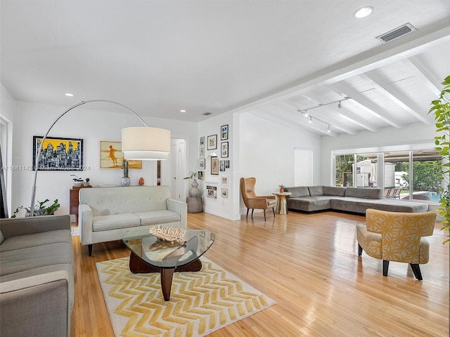 living room featuring light wood-type flooring and lofted ceiling with beams