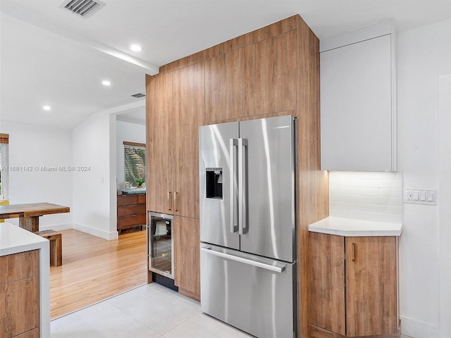 kitchen with stainless steel fridge with ice dispenser, wine cooler, light wood-type flooring, and tasteful backsplash