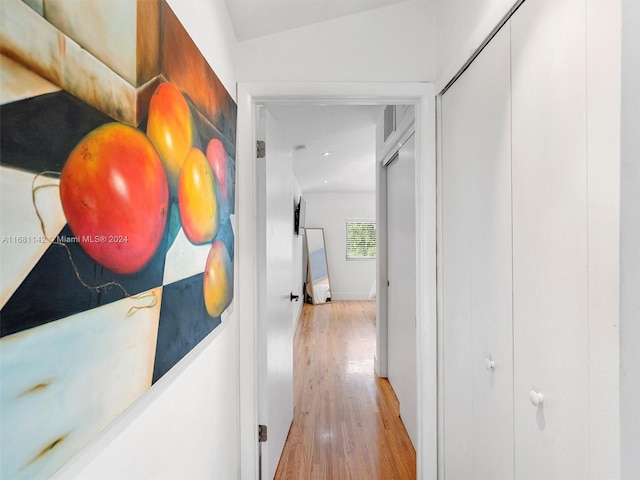 corridor featuring light hardwood / wood-style flooring and vaulted ceiling