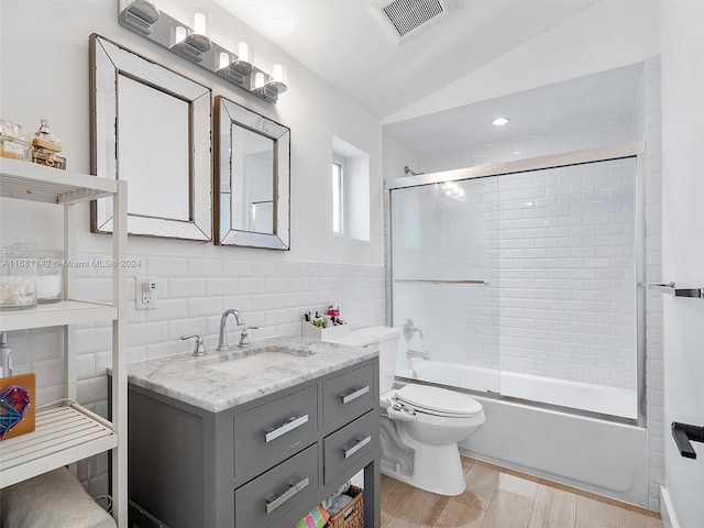 full bathroom with hardwood / wood-style flooring, shower / bath combination with glass door, vanity, lofted ceiling, and toilet