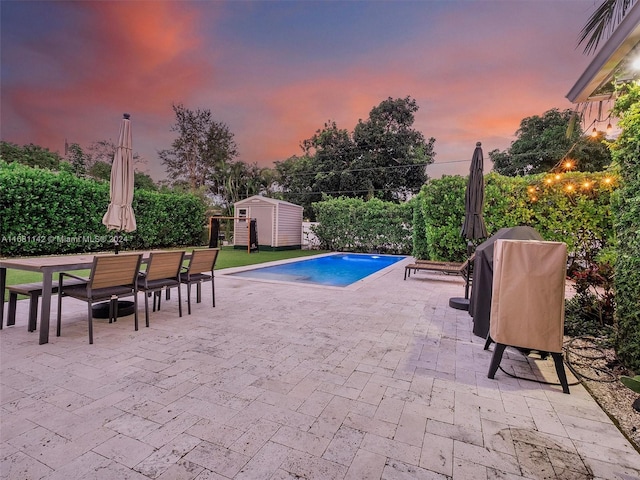 pool at dusk featuring a storage shed and a patio area