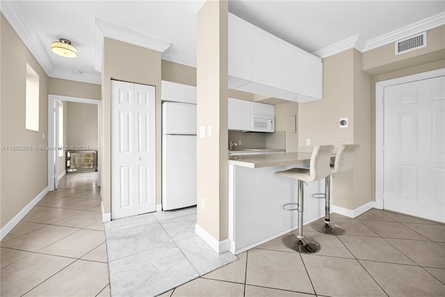 kitchen with crown molding, white cabinets, a kitchen bar, and white appliances