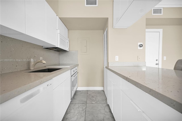 kitchen featuring sink, white cabinets, light stone counters, white appliances, and tasteful backsplash