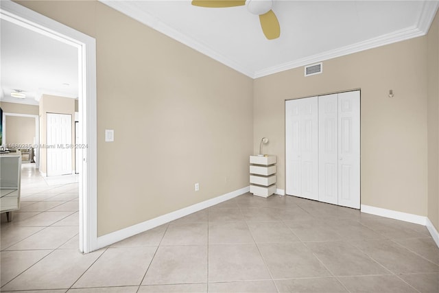 unfurnished bedroom featuring crown molding, a closet, light tile patterned floors, and ceiling fan