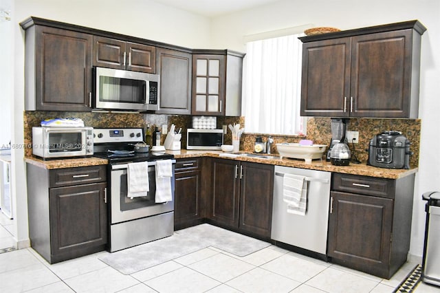 kitchen with dark brown cabinets, light tile patterned floors, and appliances with stainless steel finishes